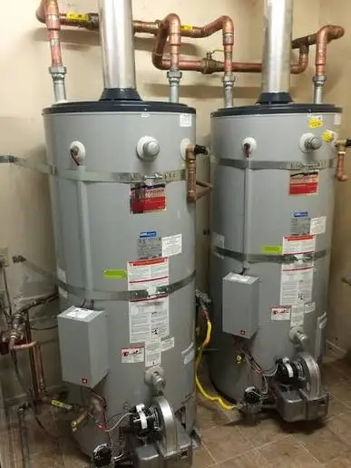 Paired commercial gas water heaters with copper piping and seismic strapping in a mechanical room